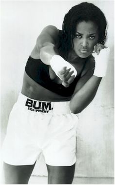 a black and white photo of a woman in boxing shorts with her arm raised up