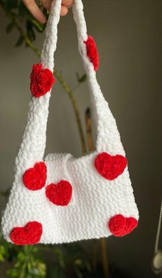 a crocheted purse with red hearts hanging from it