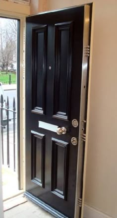 a black door is open in front of a white wall and glass doors are closed