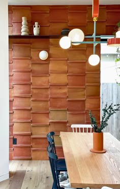 a wooden table and chairs in front of a wall with lights on it's sides