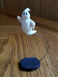 a small white ghost figurine sitting on top of a wooden table