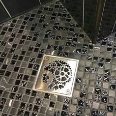 a metal grate sitting on top of a tiled floor next to a shower head