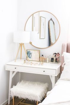 a white desk with a mirror, stool and other items on it in front of a bed