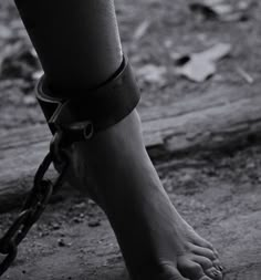 black and white photograph of a person's foot wearing a leather bracelet with words on it