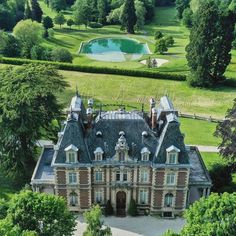 an aerial view of a large building with trees in the foreground and a pond in the background