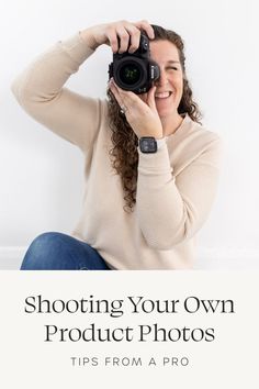 a woman sitting on the floor holding up a camera to take a photo with her hands