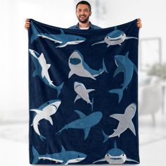 a man holding up a blanket with sharks on it