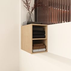 an open shelf with folded towels on it next to a vase filled with dried flowers