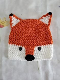 an orange and white crocheted hat with a fox face