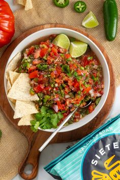 a bowl filled with salsa and tortilla chips on top of a wooden cutting board