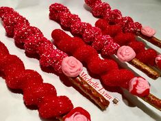 there are many red and pink candy sticks with roses on them that look like they were made out of strawberries