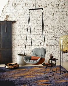 a living room with white brick walls and a swing chair in the middle of it