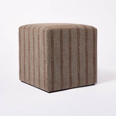 a small square ottoman sitting on top of a white floor