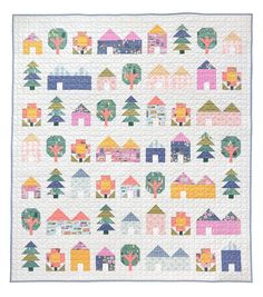 a quilted wall hanging with houses and trees on the front, in pastel colors