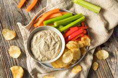 a plate with chips, carrots, celery and dip on it next to crackers