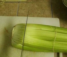 an uncooked piece of corn on a cutting board