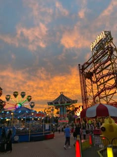 an amusement park at sunset with people walking around