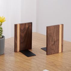 two wooden blocks sitting on top of a table next to a potted plant and phone