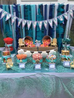 a table topped with lots of food next to a blue and white wall covered in streamers