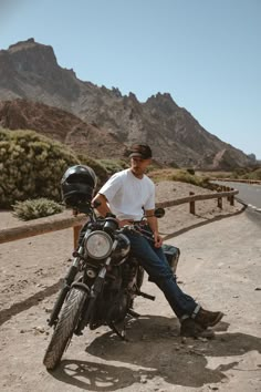 a man is sitting on his motorcycle in the desert