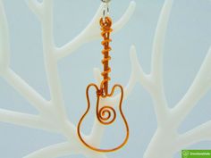 an orange wire is hanging from a metal hook with a guitar charm attached to it