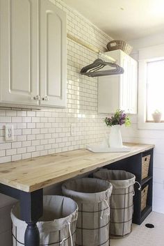 three buckets sitting on top of a wooden counter in a white tiled kitchen area