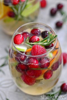 two glasses filled with fruit and veggies on top of a white tablecloth