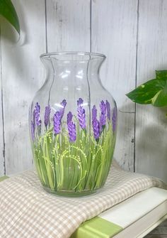 a glass vase with purple flowers painted on it