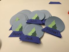 several pieces of paper cut out to look like trees with name tags in the middle