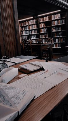 an open book on a wooden table in front of a library full of bookshelves