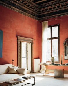 a living room with red walls and white furniture