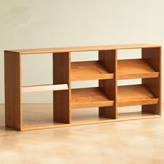 a wooden shelf with several shelves on top of it and a white wall in the background