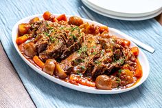 a white plate topped with meat and potatoes on top of a blue table cloth next to a fork