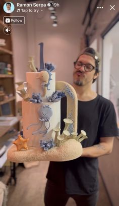 a man holding a cake decorated with blue and white decorations