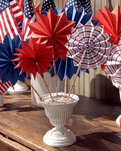 red, white and blue pinwheels are in a vase on a wooden table