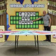 a man standing in front of a table that is made to look like a wheel of fortune