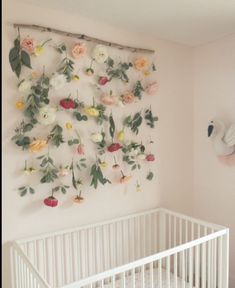 a white crib with flowers hanging on the wall