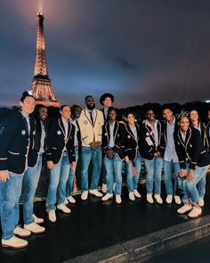 a group of men standing next to each other in front of the eiffel tower