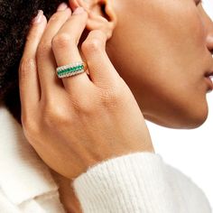 a close up of a person wearing a ring with an emerald stone on the side