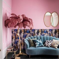 a living room with pink walls, blue couches and gold mirrors on the wall