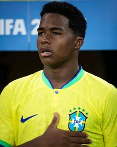 a soccer player giving the thumbs up sign in front of a blue and yellow wall