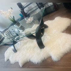 a glass table topped with a black cat head on top of a white sheepskin rug