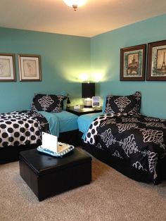 two beds in a room with blue walls and black and white comforters on them