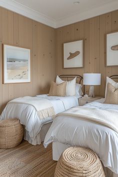 two beds in a room with white linens and brown wood paneling, one has a wicker basket on the floor