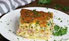 a white plate topped with lasagna covered in meat and cheese on top of parsley