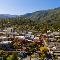 an aerial view of a city with mountains in the background and trees on both sides