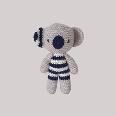 a small crocheted koala bear hanging from a hook on a gray wall