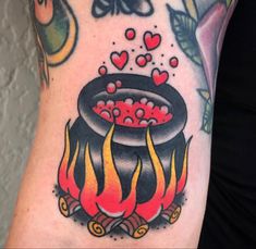 a woman's arm with a pot on fire and hearts