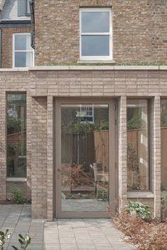 a brick building with an open door and glass windows on the outside, in front of a patio area