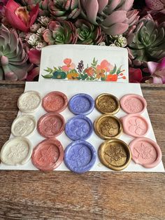 a bunch of wax seals sitting on top of a wooden table next to some flowers